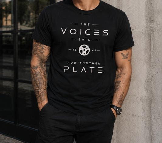 Person wearing a black t-shirt with white text and design, standing against a concrete wall.