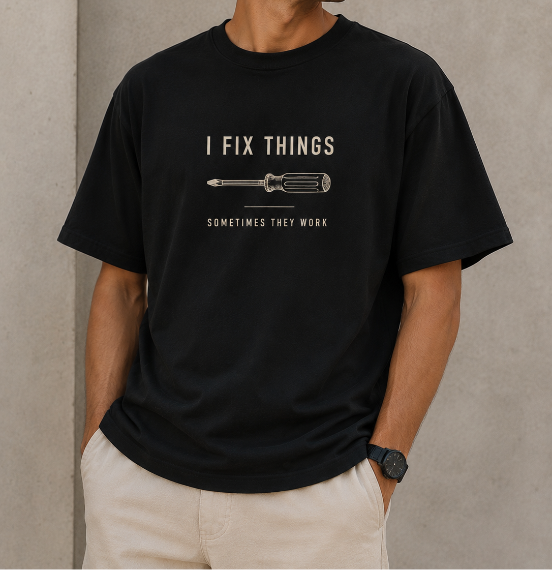 Man wearing a black t-shirt with a graphic and text against a gray wall.