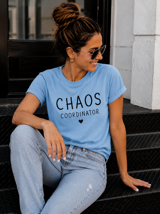 A Woman with her hair tied in a bun wearing blue tee shirt with quote "CHAOS COORDINATOR" written on it . Matching tee shirt for mother and daughter